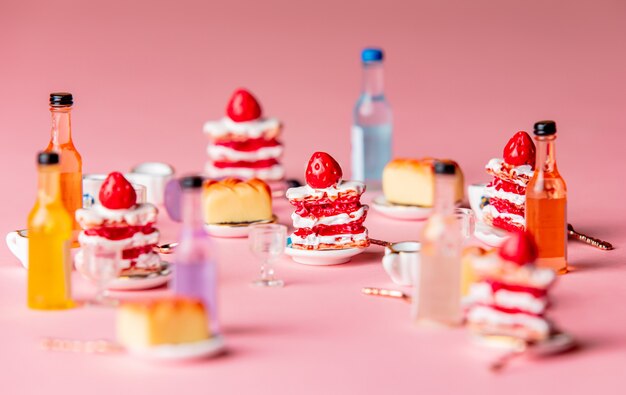 Photo gâteaux miniatures et boisson sur fond rose