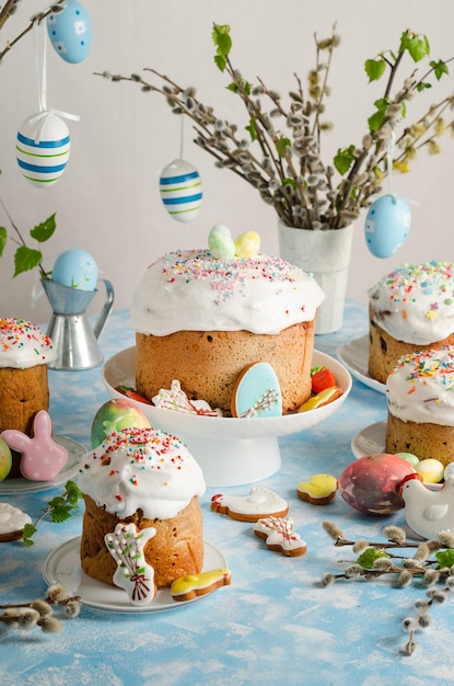 Gâteaux et oeufs de Pâques sur une table de fête de Pâques avec saule et figurine d'un lapin sur fond bleu