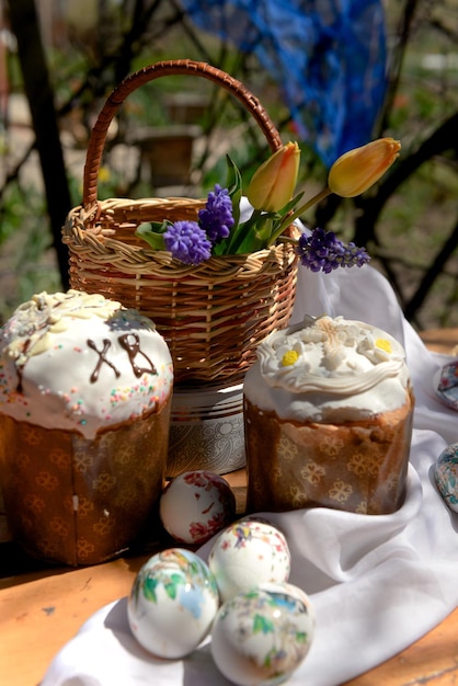 Gâteaux de Pâques oeufs et tulipes jaunes et fleurs violettes dans un panier le jour de Pâques