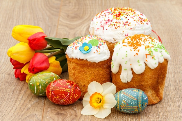 Gâteaux de Pâques sucrés oeufs de Pâques peints narcisse tulipes rouges et jaunes sur fond de bois