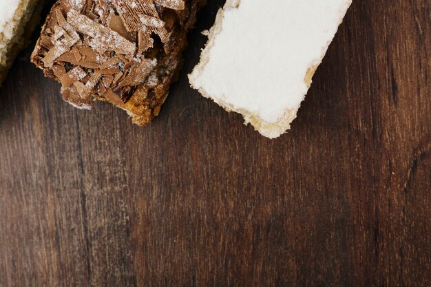 Gâteaux de pâte feuilletée avec du sucre en poudre et de la crème et un autre avec du chocolat et une cerise sur la table en bois. Vue de dessus et espace pour le texte. Mise au point sélective.