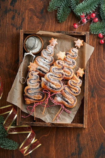 Gâteaux de pâte feuilletée en forme d'arbre de Noël avec de la poudre de sucre de remplissage au chocolat et des sucettes sur fond de bois ancien