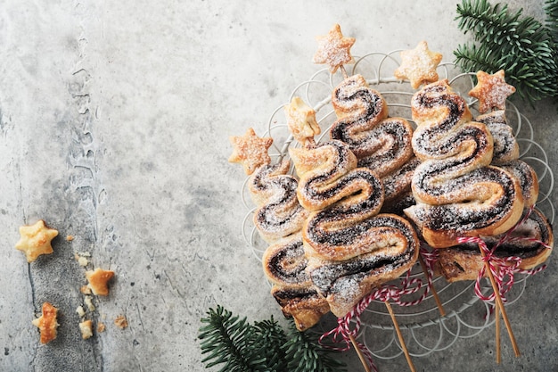 Gâteaux de pâte feuilletée en forme d'arbre de Noël avec de la poudre de sucre de remplissage au chocolat et des sucettes sur un vieux fond en bois blanc