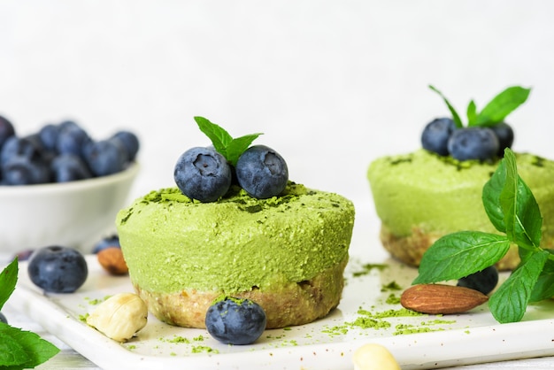 Gâteaux de poudre de matcha crus faits maison avec des baies fraîches, de la menthe, des noix. concept de nourriture végétalienne saine