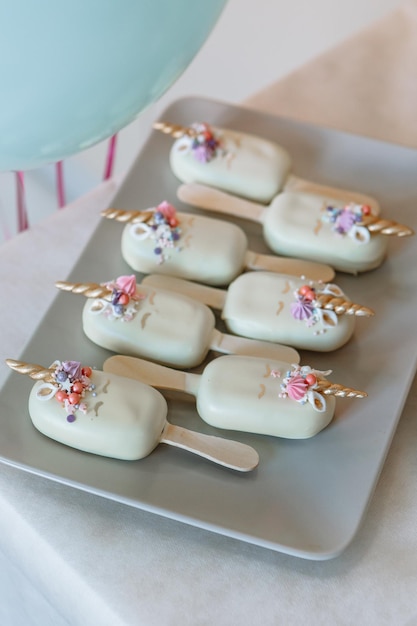 Les gâteaux sont sur une assiette Gâteaux en glaçure blanche avec l'image d'une corne de licorne Anniversaire