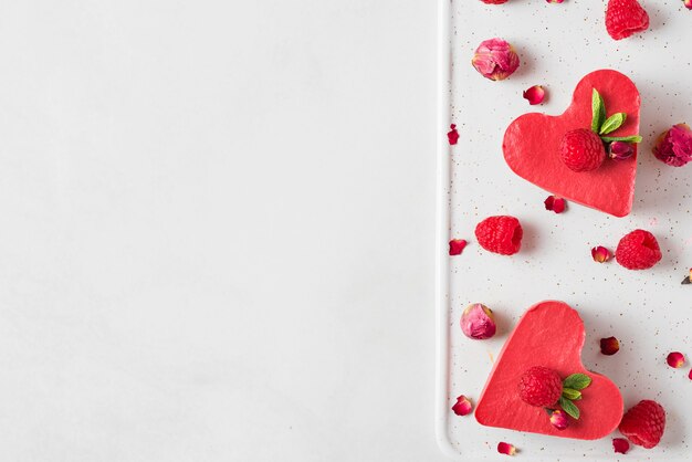 Gâteaux végétaliens crus rouges en forme de coeur avec des framboises fraîches, de la menthe et des fleurs séchées. Dessert de la Saint-Valentin. vue de dessus