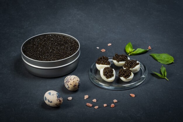 Gâterie festive du Nouvel An. Sandwichs à l'esturgeon caviar noir sur une plaque ronde bleue sur une surface sombre.