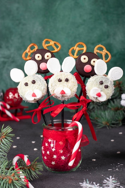 Gâteries de Noël cake pops Lapins et rennes du Père Noël à partir de cookies dans des flocons de noix de coco au chocolat guimauves et craquelins sur fond vert