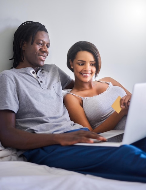 Gâtez-la dans la chambre Photo d'un jeune couple faisant des achats en ligne avec une carte de crédit