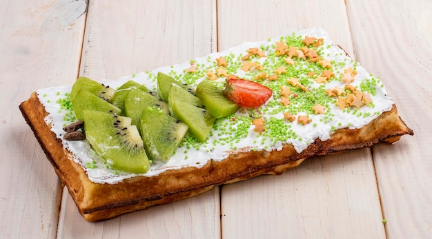 Gaufre belge à la crème de fraises et de kiwi Sur un fond de bois clair