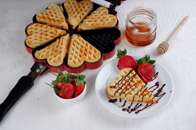 Gaufre belge avec du miel de fraise fraîche et du chocolat sur blanc