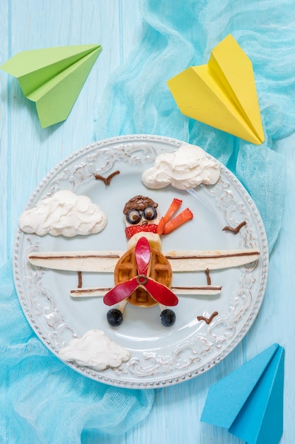 Gaufre drôle de petit déjeuner d'avion avec des fruits pour des enfants de garçon