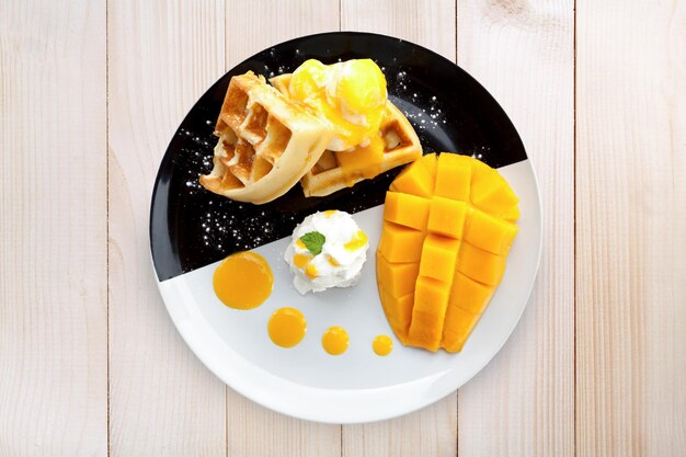 Gaufre vue de dessus avec crème glacée et mangue sur table en bois