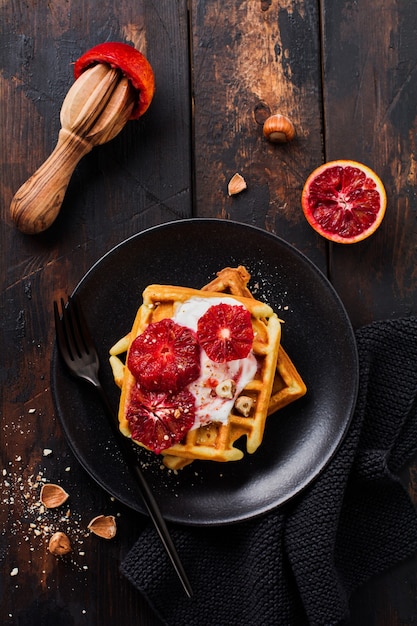 Gaufres au yogourt et sauce à l'orange sicilienne rouge sur la vieille surface en bois sombre. Vue de dessus.