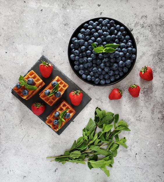 Gaufres aux fraises fraîches, bleuets et un brin de menthe sur fond clair