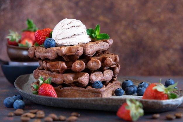 Gaufres belges au chocolat avec baies fraîches et glace au café sur une assiette en céramique sur une table marron