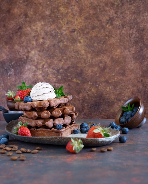 Gaufres belges au chocolat avec baies fraîches et glace au café sur une assiette en céramique sur une table marron