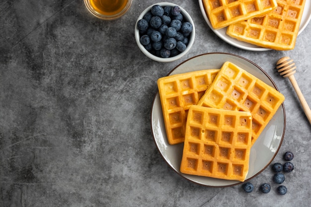 Gaufres belges aux myrtilles et au miel pour le petit déjeuner. Délicieuse pâtisserie maison. Copiez l'espace.