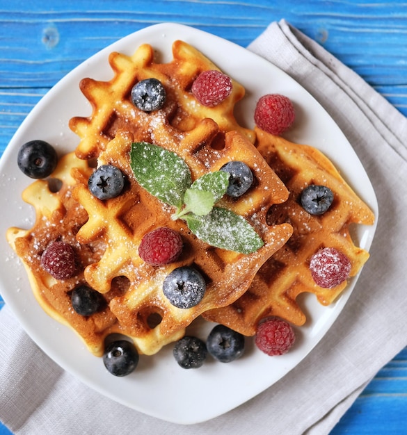 Gaufres belges aux myrtilles framboises et sucre en poudre sur table en bois