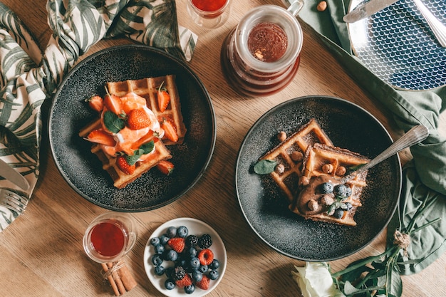 Gaufres belges avec baies, glace et chocolat. Réglage de la table du petit déjeuner. Style de vie du matin.