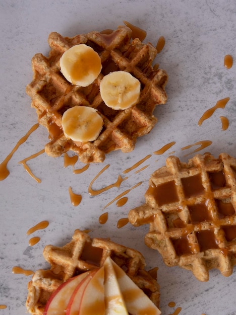 Photo gaufres belges faites maison avec des fruits frais pomme banane et caramel sur fond de texture grise