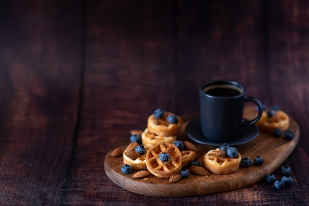 Gaufres belges faites maison, tasse en céramique blanche de café, lait, cuillère à café et grains de café.