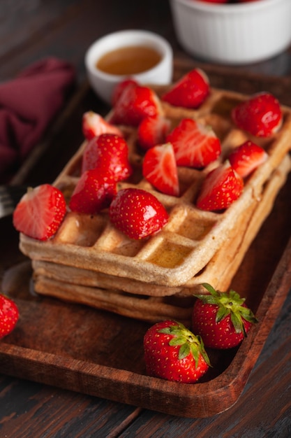 Photo des gaufres belges fraîches faites maison sur une vieille table en bois avec des fraises et du miel