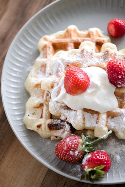 Photo gaufres belges à la fraise et au sucre en poudre sur fond de table en bois