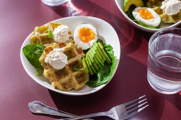 Gaufres belges avec œuf au fromage à la crème et avocat dans une assiette blanche Petit-déjeuner sain