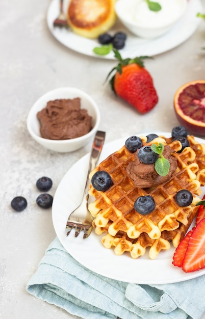 Gaufres belges avec sauce au chocolat, baies, menthe et pancakes