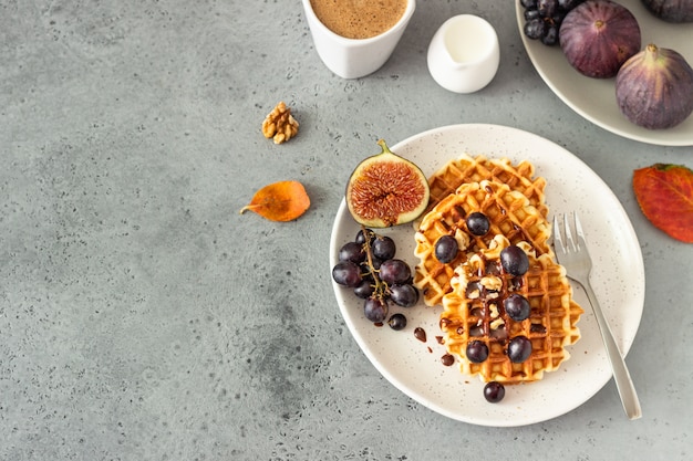 Gaufres belges traditionnelles avec sauce au caramel, raisins et figues. Petit-déjeuner d'automne ou d'hiver confortable.