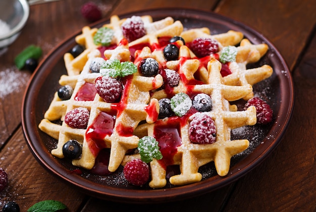 Photo gaufres de belgique aux framboises et sirop sur une assiette.