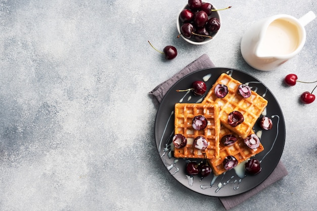 Gaufres cannelées belges aux cerises fraîches et crème sur une assiette