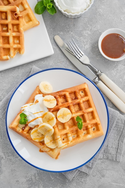 Gaufres à la crème fouettée à la banane et au caramel salé sur fond de béton gris