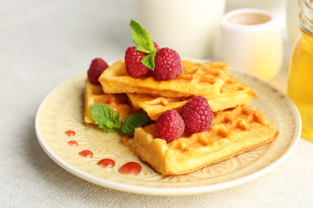 Gaufres maison sucrées avec framboises fraîches sur assiette, sur surface légère