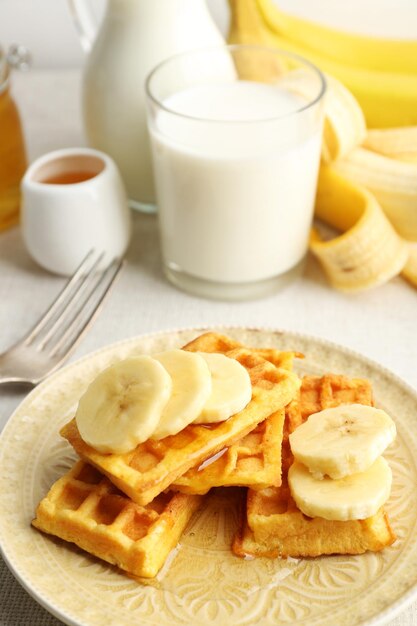 Gaufres maison sucrées avec tranches de banane sur plaque sur fond clair