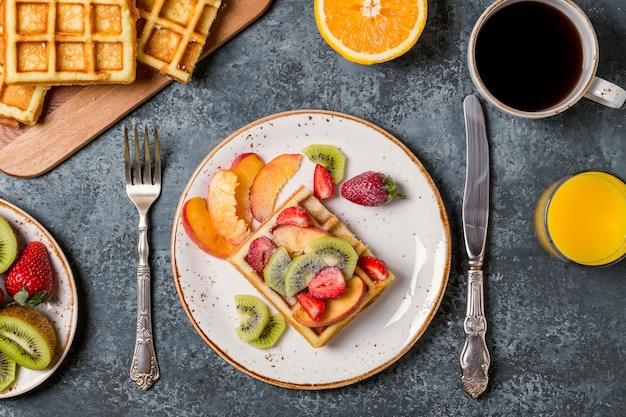 Gaufres de petit-déjeuner avec des fruits frais sur la surface en béton