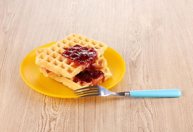 Gaufres savoureuses avec de la confiture sur plaque sur fond de bois