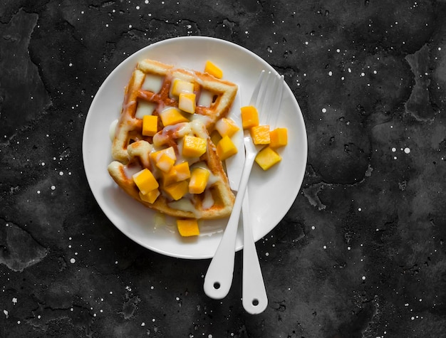 Gaufres sucrées à la mangue et dulce de leche sur une vue de dessus de fond sombre