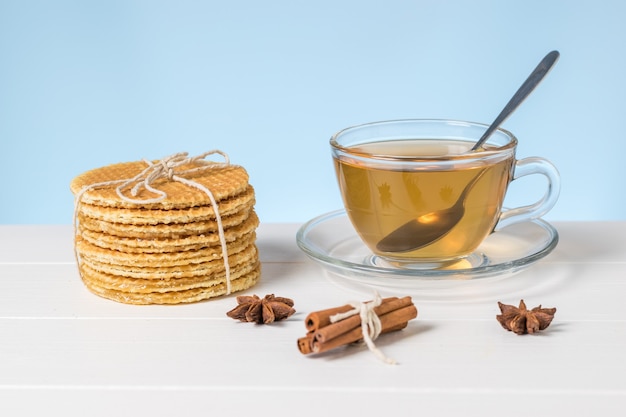 Gaufres et thé faits maison dans une tasse en verre sur un tableau blanc sur fond bleu. Gâteaux faits maison avec du thé.