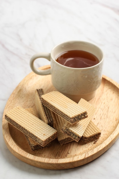 Gaufrette au chocolat sur plaque de bois, servie avec du thé, espace de copie