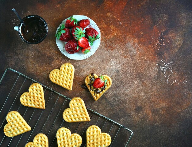 Gaufrettes au chocolat et fraises sur fond marron, vue de dessus