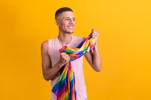 Gay pride garçon homosexuel tenant le drapeau lgbt sur fond jaune