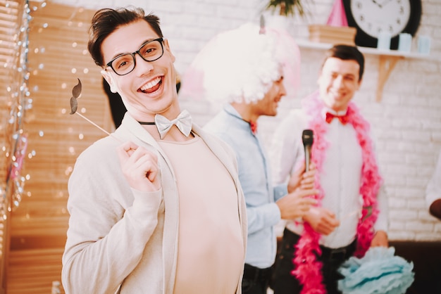 Gays avec des noeuds papillon chantant des chansons de karaoké à la fête.