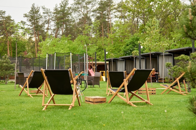 Gazebo d'alcôve en bois dans le club de golf de campagne de banlieue. L'endroit pour les loisirs longe, Chaises longues. Sortes sur le terrain de jeu Rebondir et sauter sur le trampoline dans la cour arrière