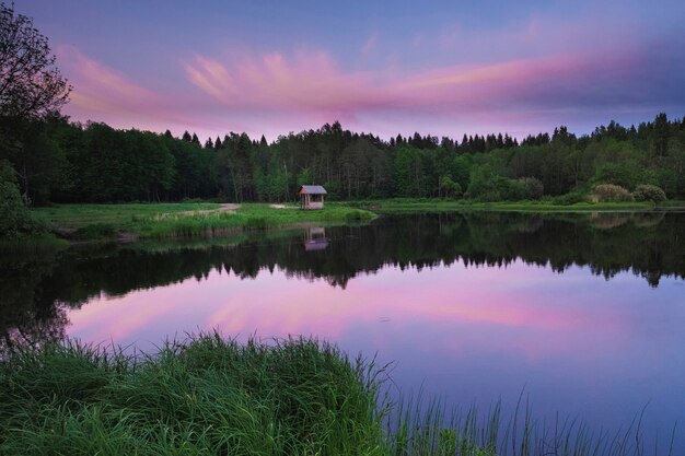 Gazebo au bord d'un lac forestier au coucher du soleil, en été