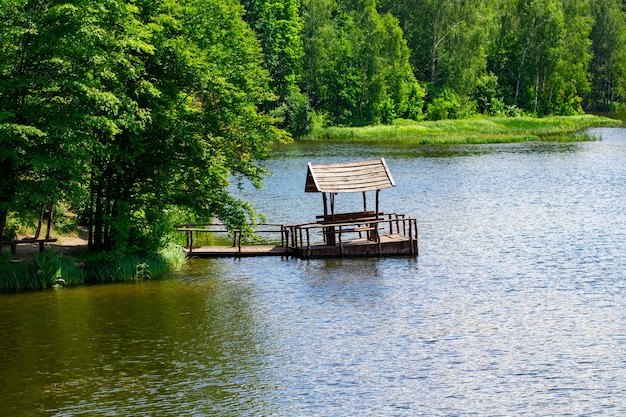 Gazebo relaxant construit sur la rivière contre la forêt.