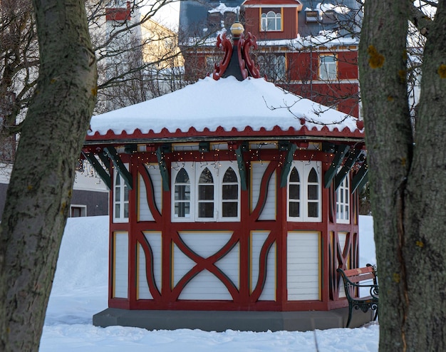 Gazebo victorien rouge et blanc avec toit couvert de neige dans le jardin d'un manoir de Reykjavik