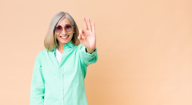 Âge moyen jolie femme portant des lunettes de soleil contre le mur de l'espace de copie