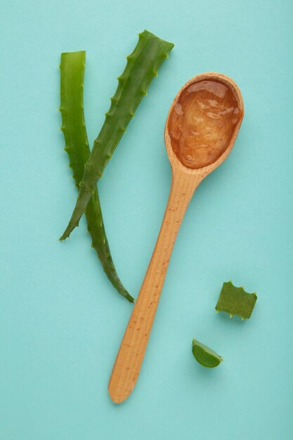 Gel d'aloe vera sur cuillère en bois à l'aloe vera sur fond bleu.